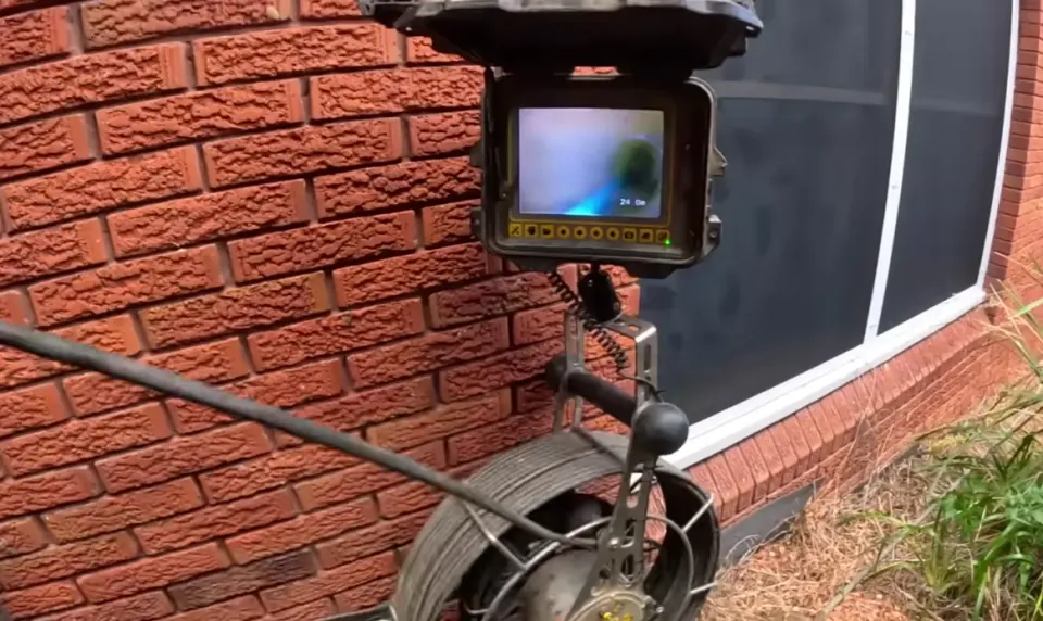 Drain inspection monitor displaying the inside of a pipe beside a cable reel.